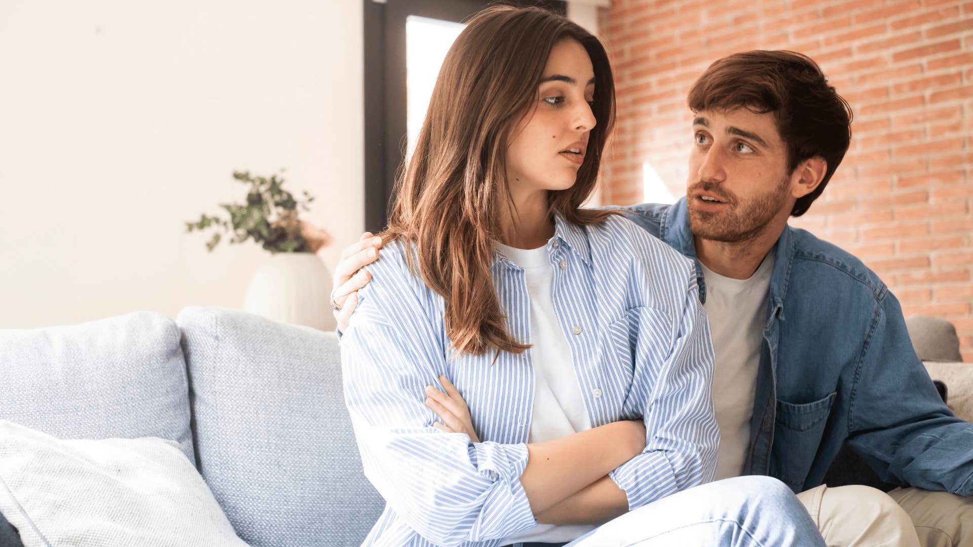 woman crossing arms at man as they're demanding