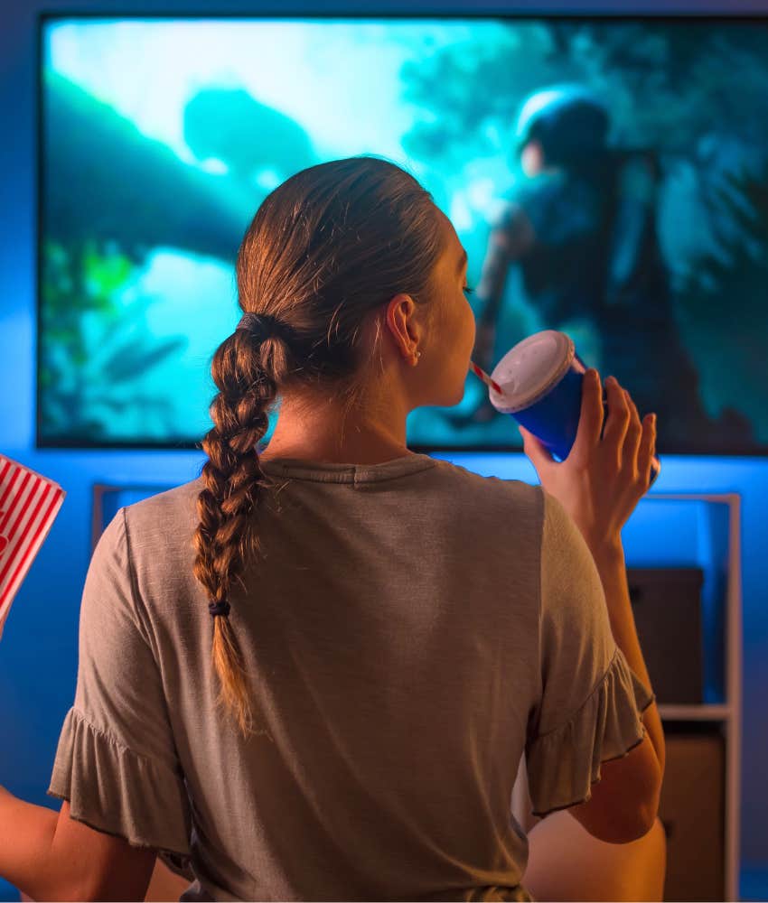 Woman hungrily eating junk food in front of the TV