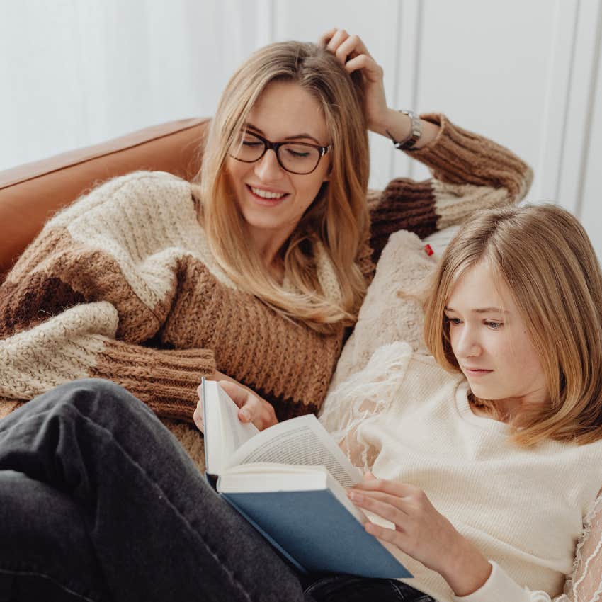 middle child reading a book laying next to her mom