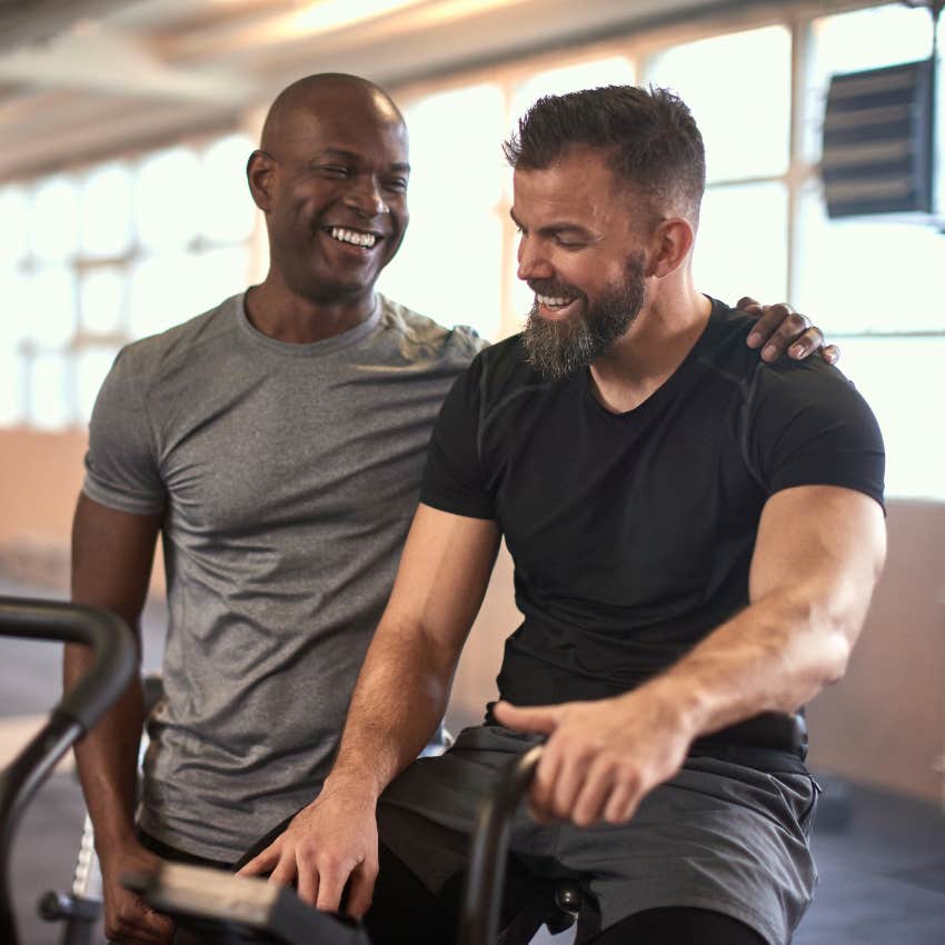 incompetent man with arm around friend at the gym telling him he is better at physical fitness