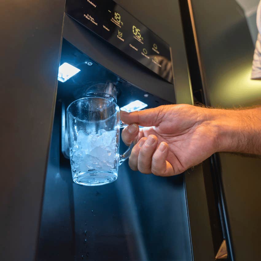 person filling cup with fridge water and ice