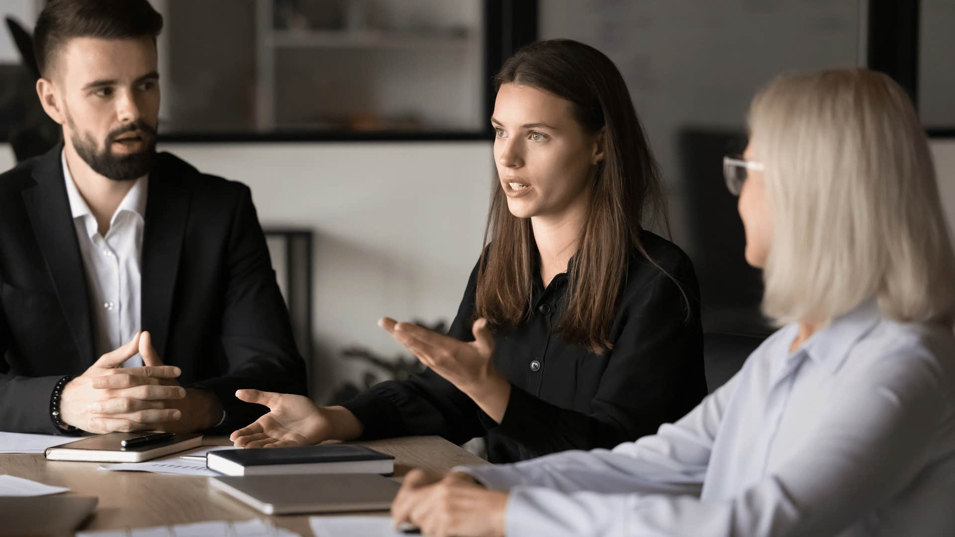 woman in black shirt in meeting telling coworkers it's better to play it safe
