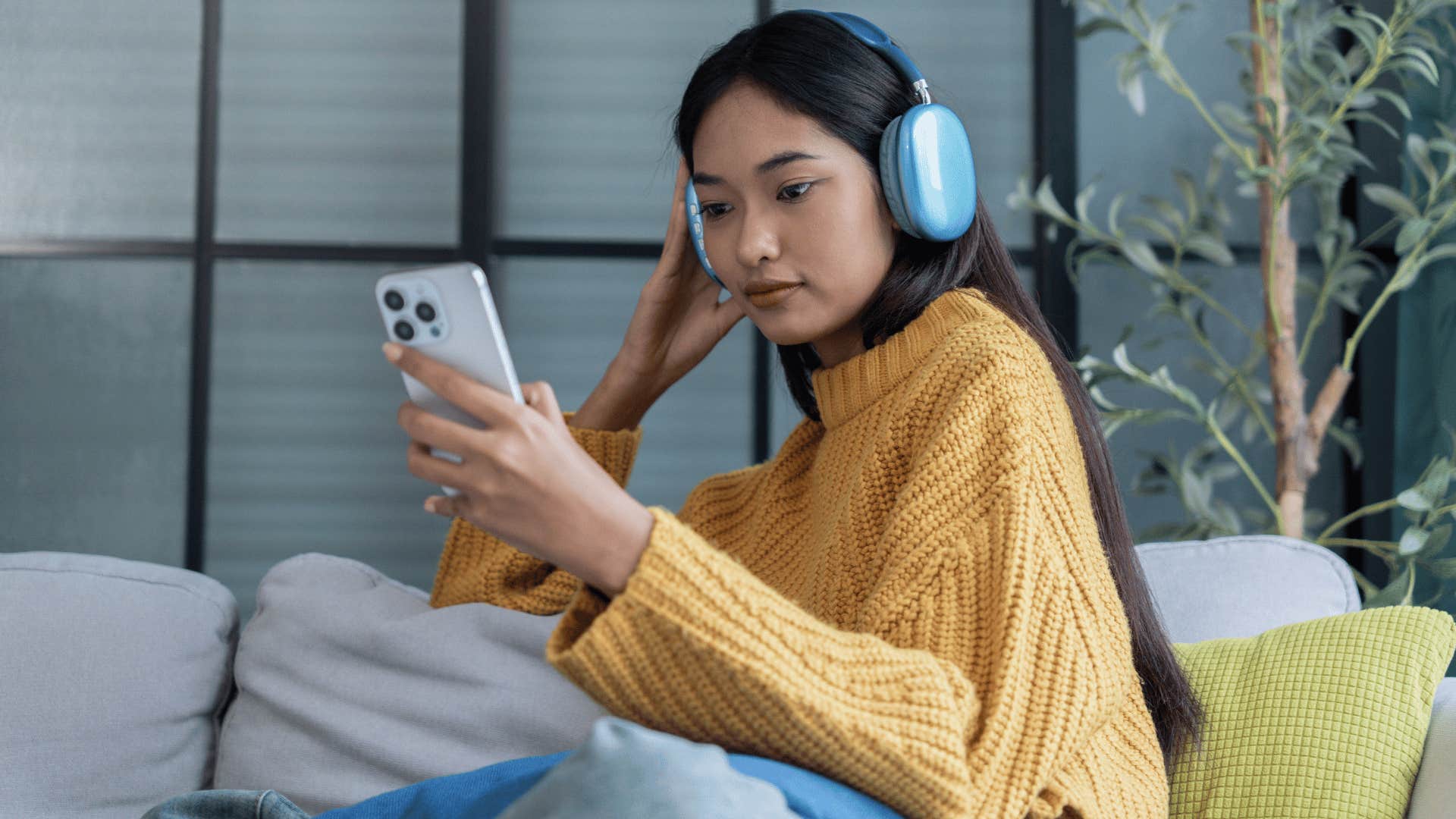woman in yellow sweater listening to educational podcasts as she looks at phone