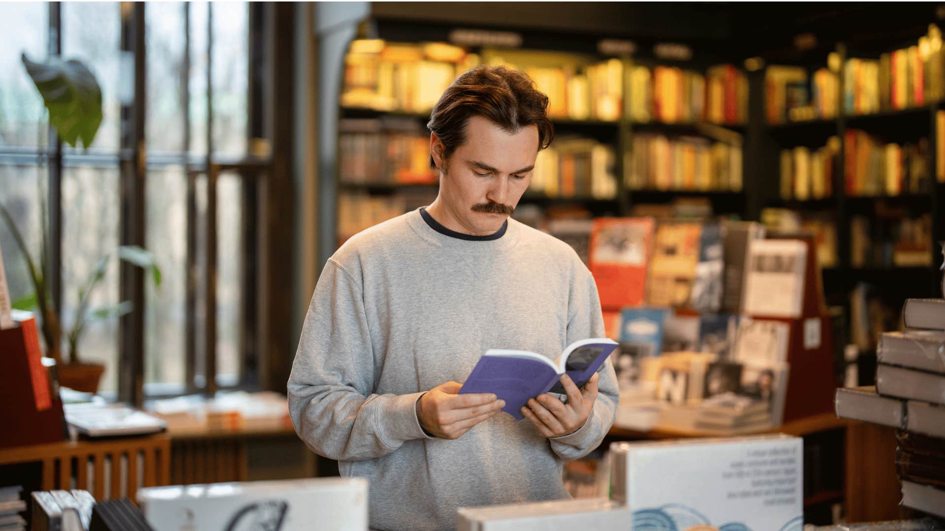 man in gray sweatshirt reading books
