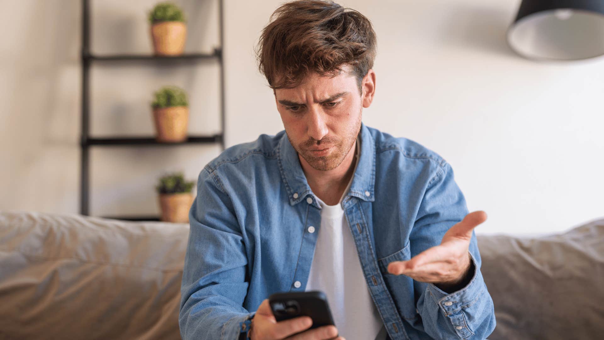 man frustrated at phone as he thinks that still doesn't answer the question