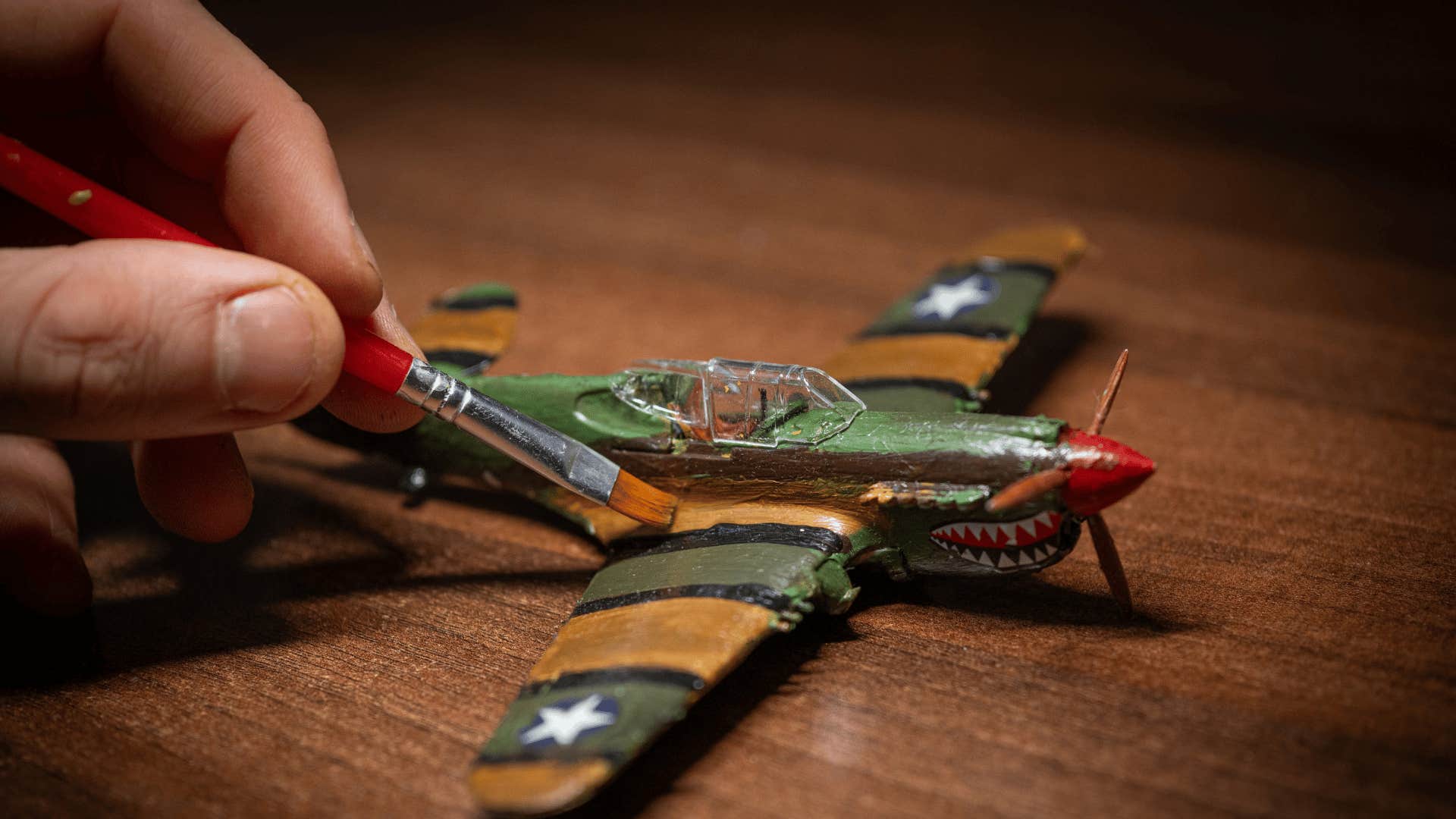 man building models as he paints airplane
