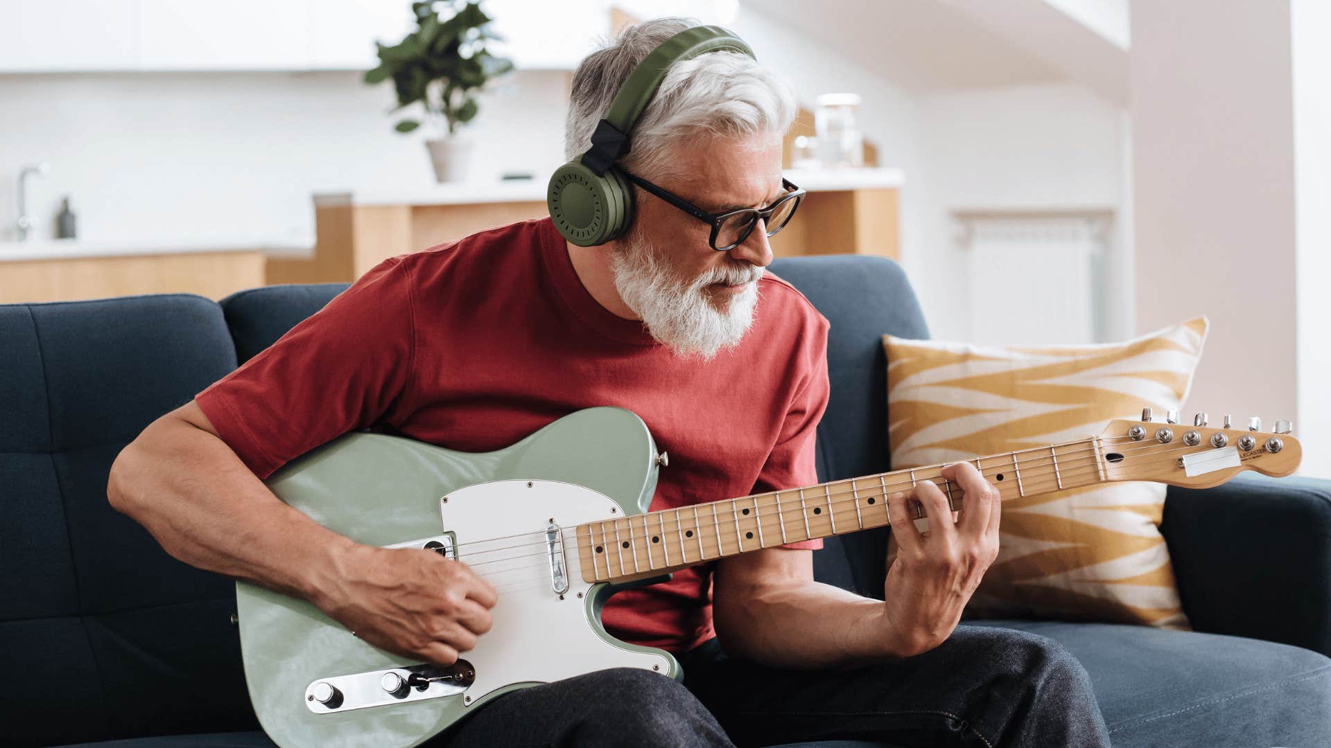 man in his 60s playing guitar at home