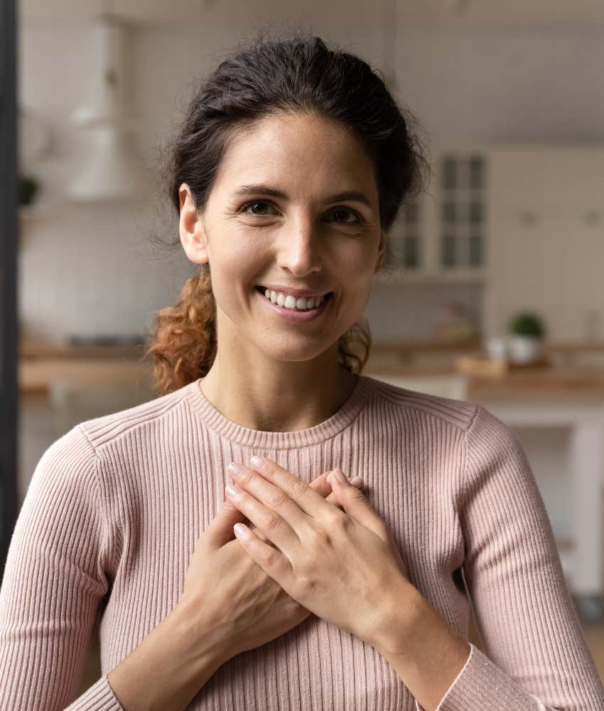 Woman who is self-regulating with hands over her heart and warm smile 