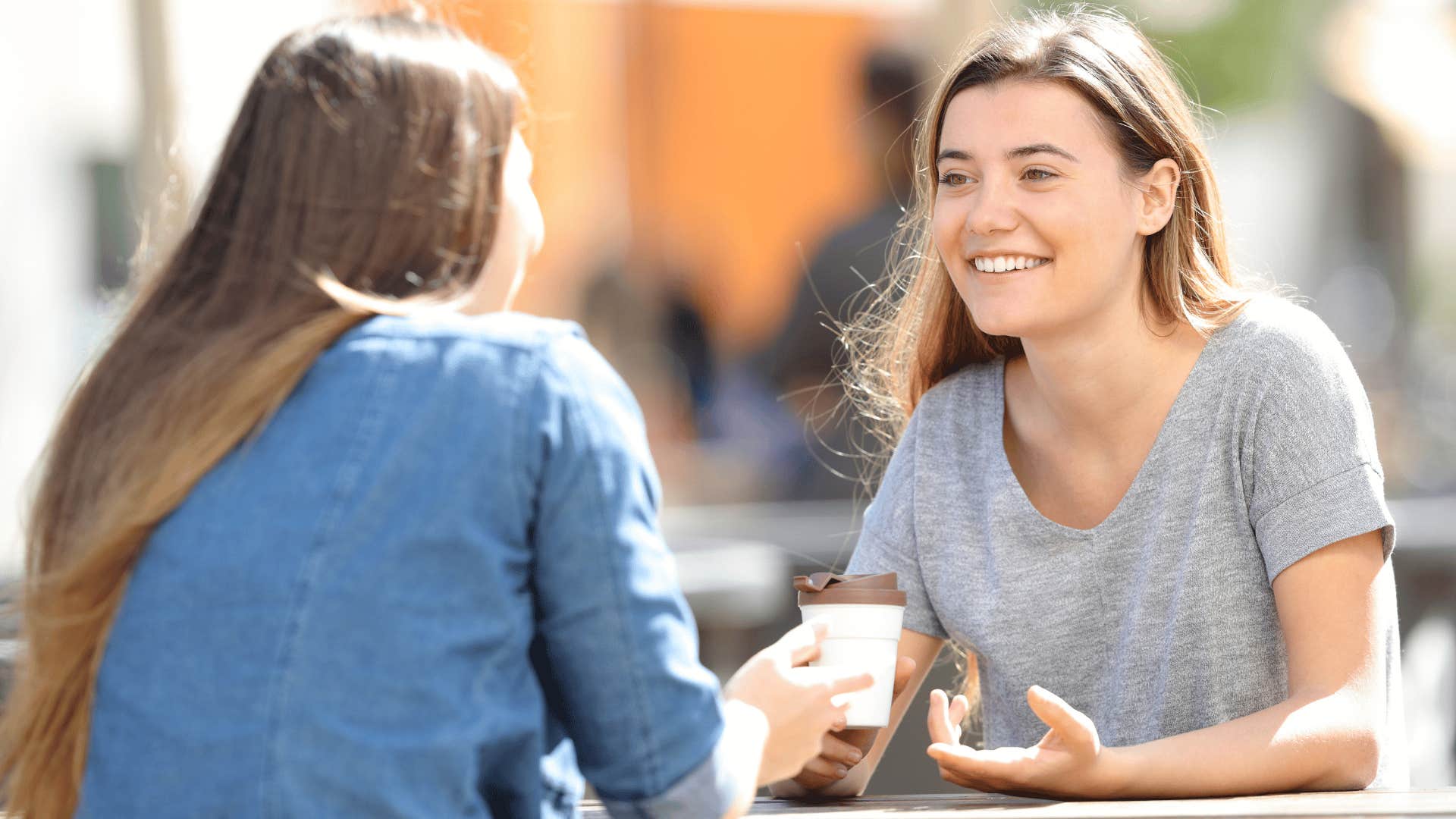woman in gray shirt smiling brightly at friend as she says i can admit when i'm wrong