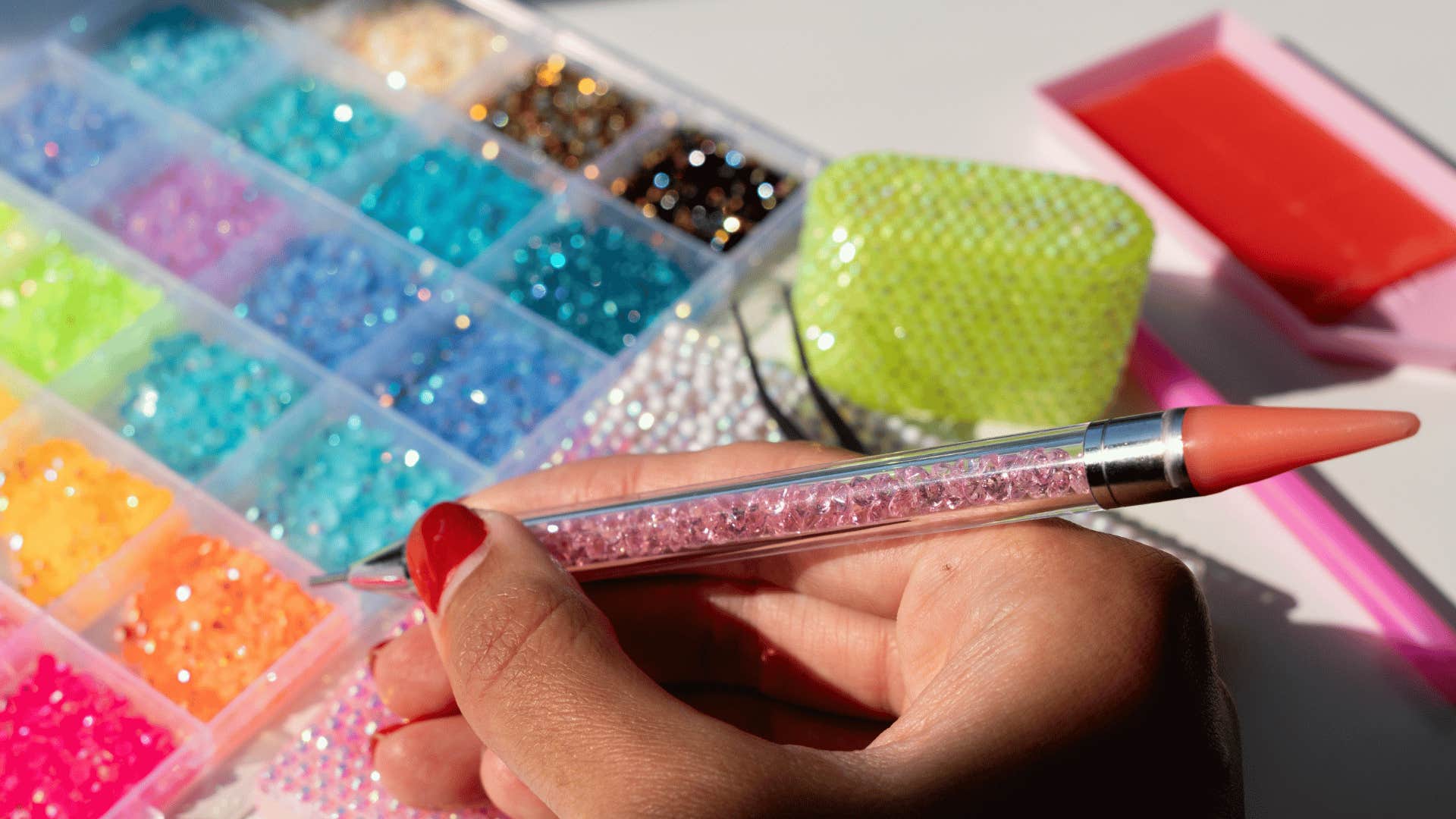 woman with red nails bedazzling accessories