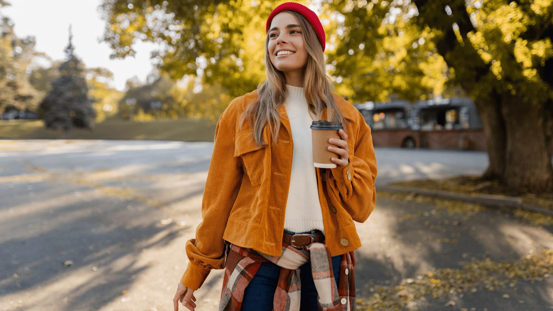 woman with orange jacket taking peaceful nature walks with cup of coffee in hand