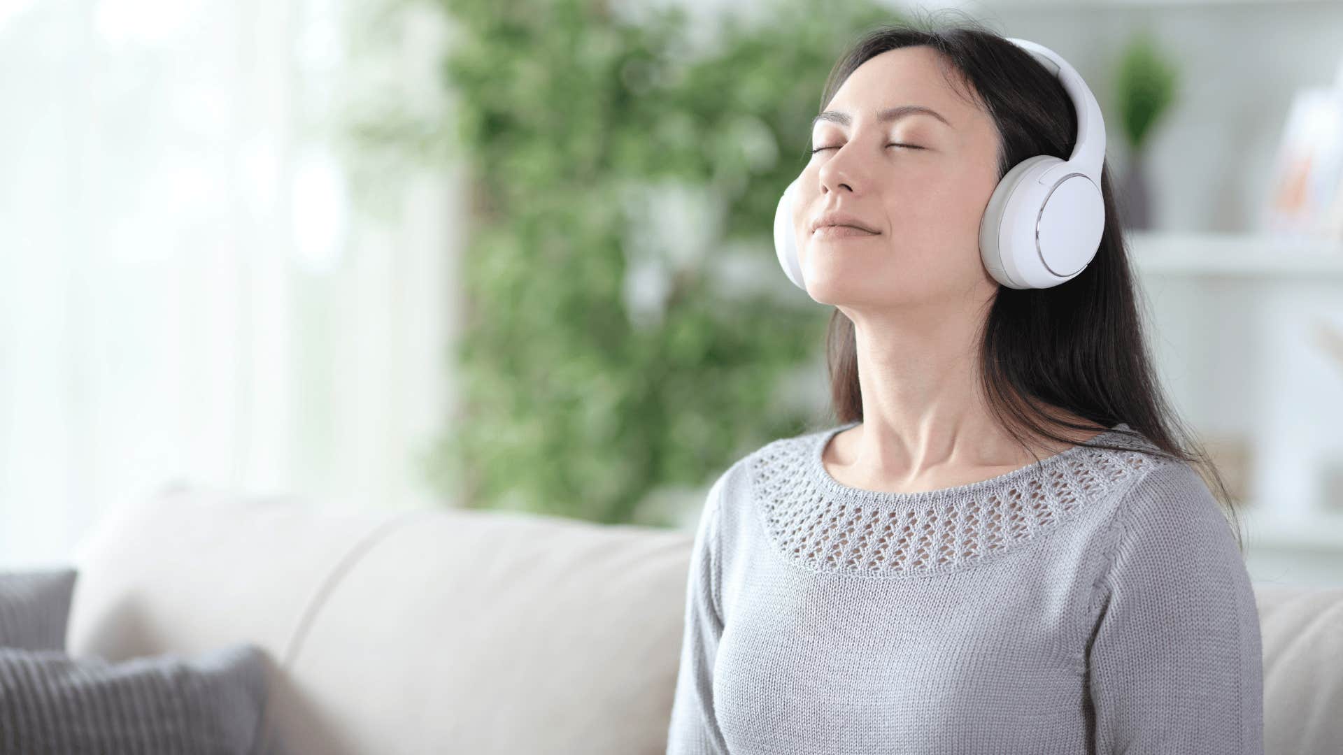 woman with gray shirt and white headphones meditating