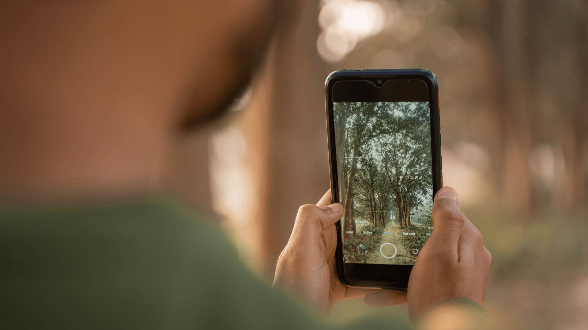 man with phone taking pics of forest as he practices photography skills