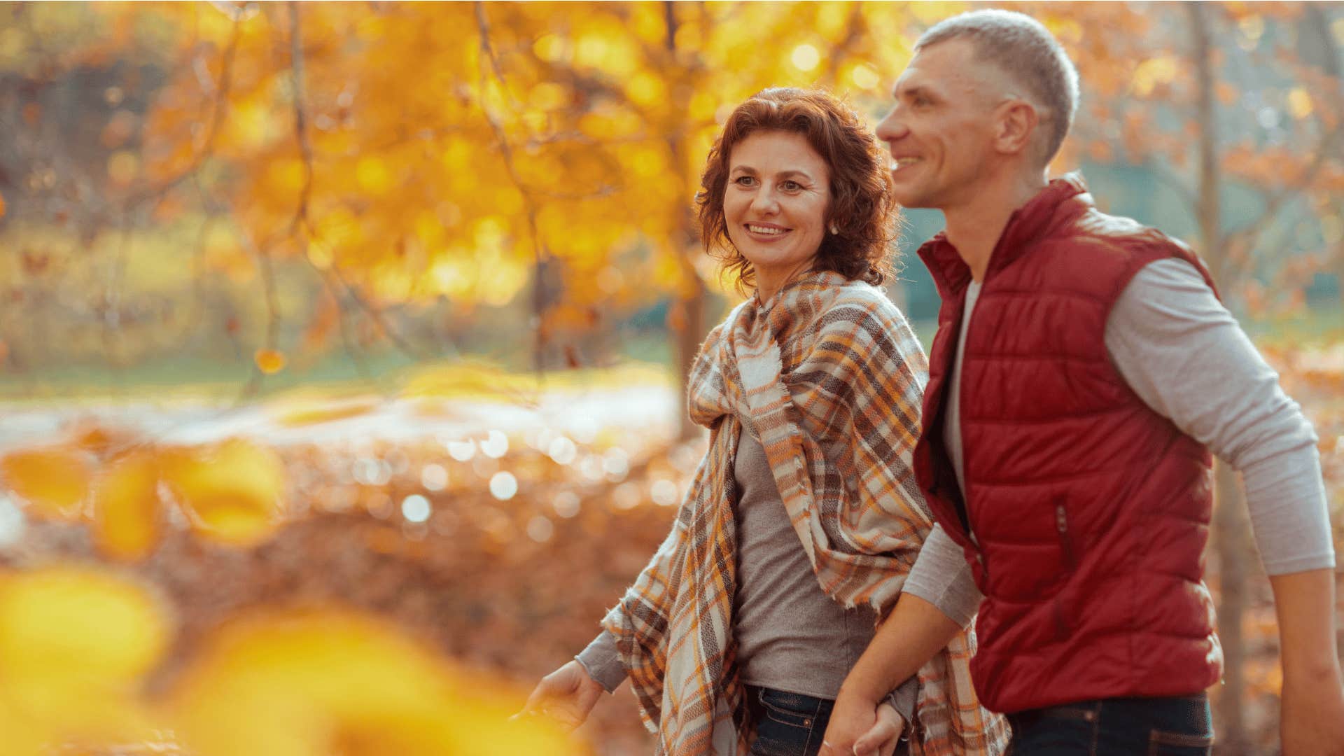 older couple walking in nature and holding hands while smiling