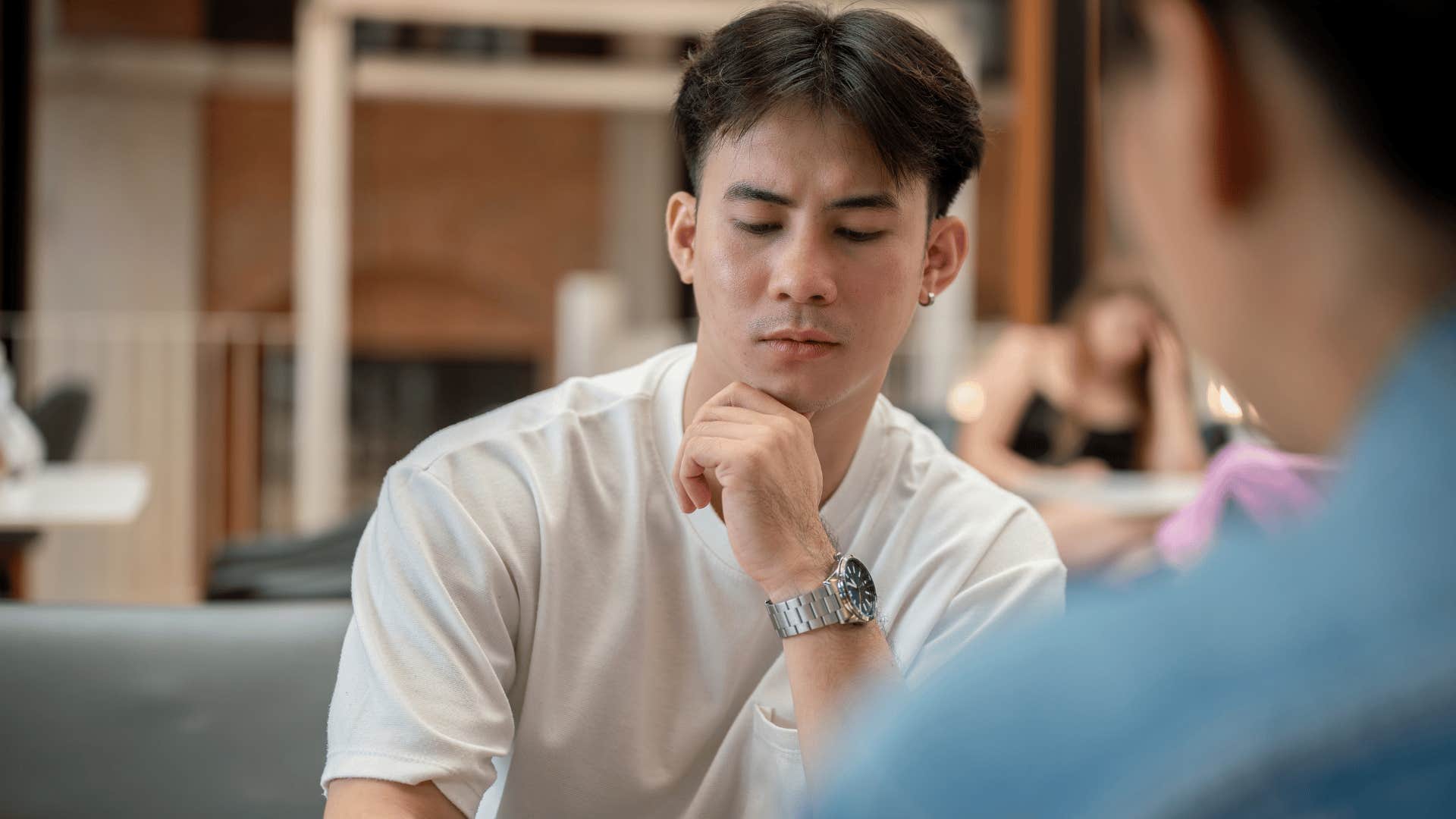 man in white shirt looking down as he tells friend i can't take you seriously right now