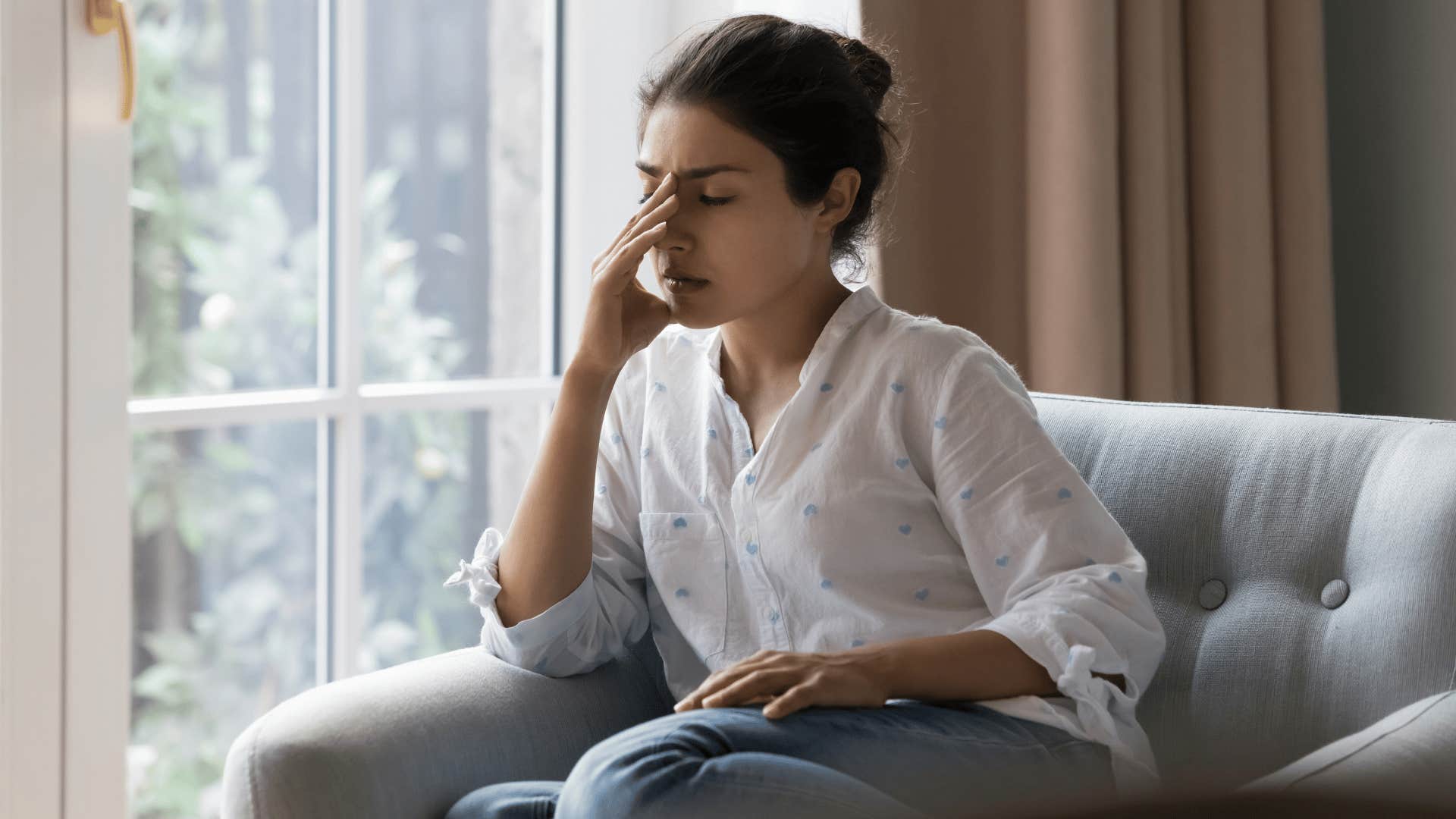woman in white shirt frustrated and covering face as she thinks i have enough going on in my life already