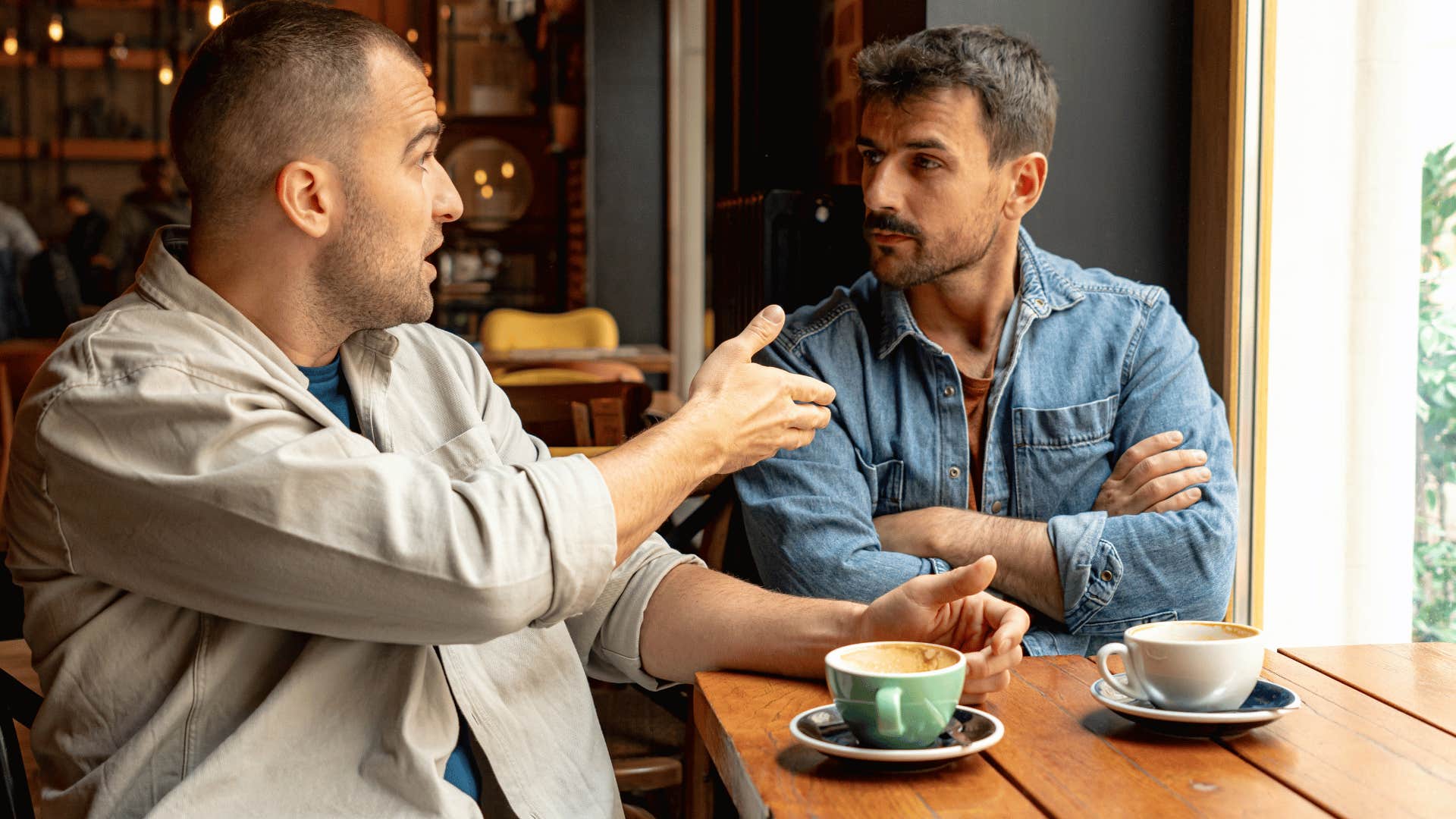 man pointing at friend telling him over coffee they need to figure it out on their own