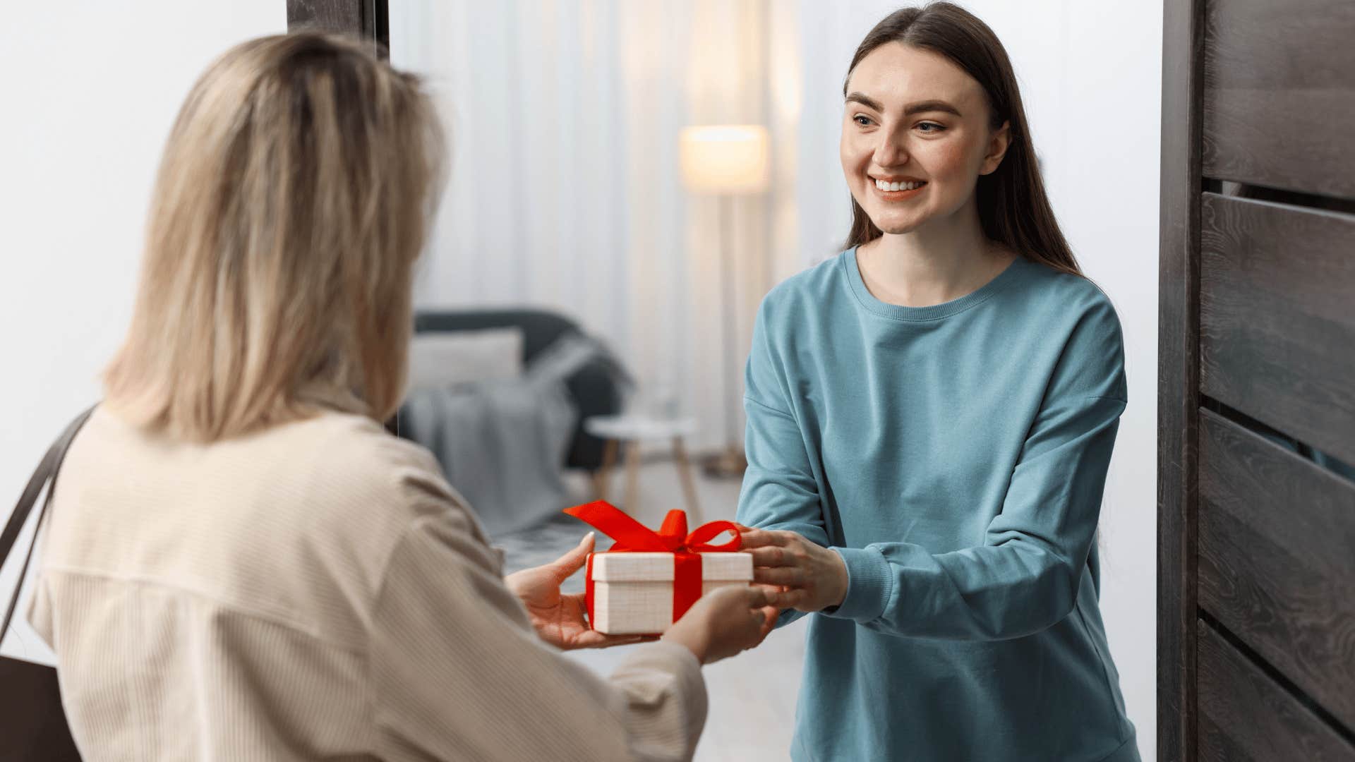 woman in beige shirt giving gift to woman without expecting anything in return