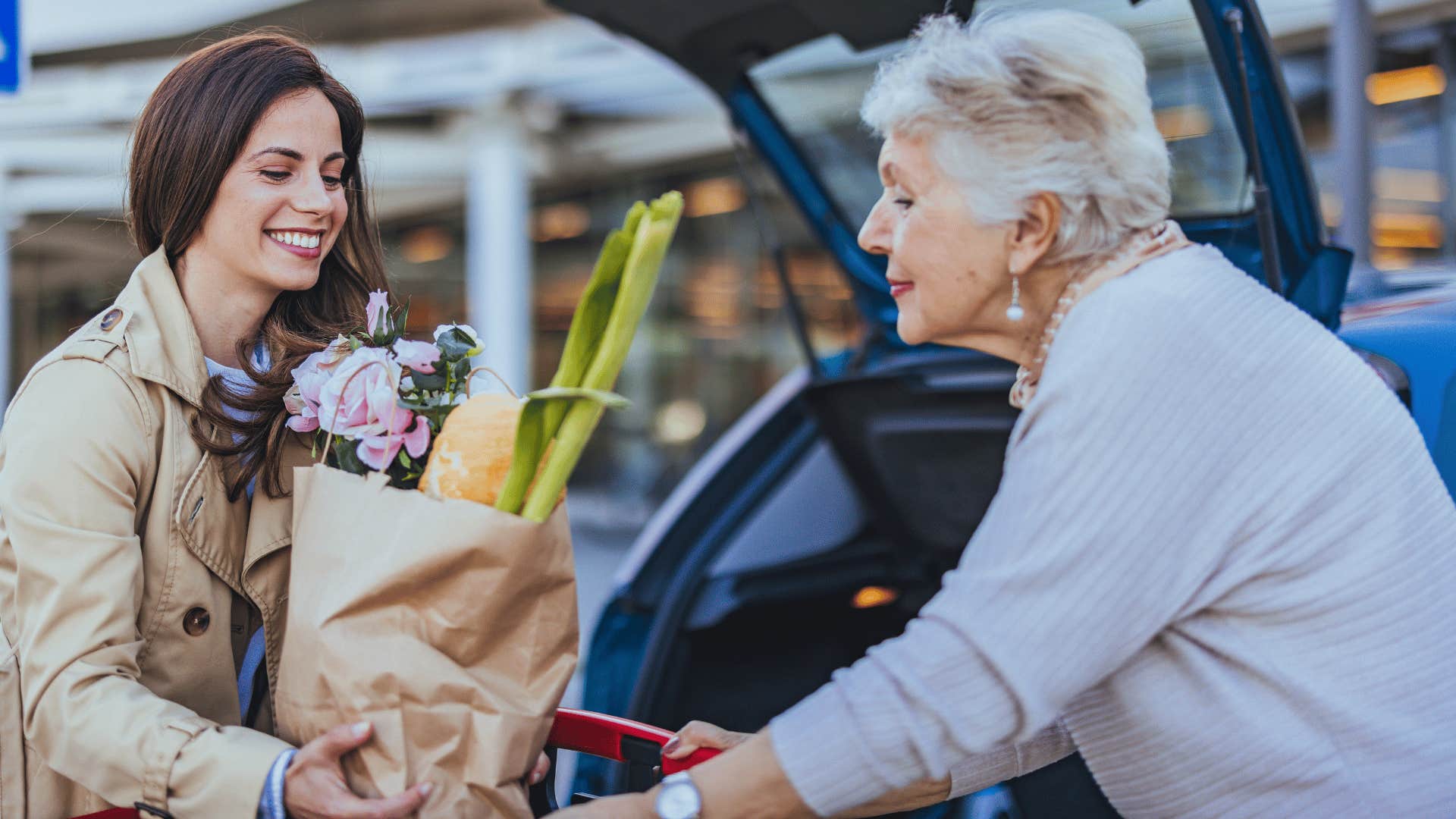 woman in beige jacket smiling as they help old woman in need