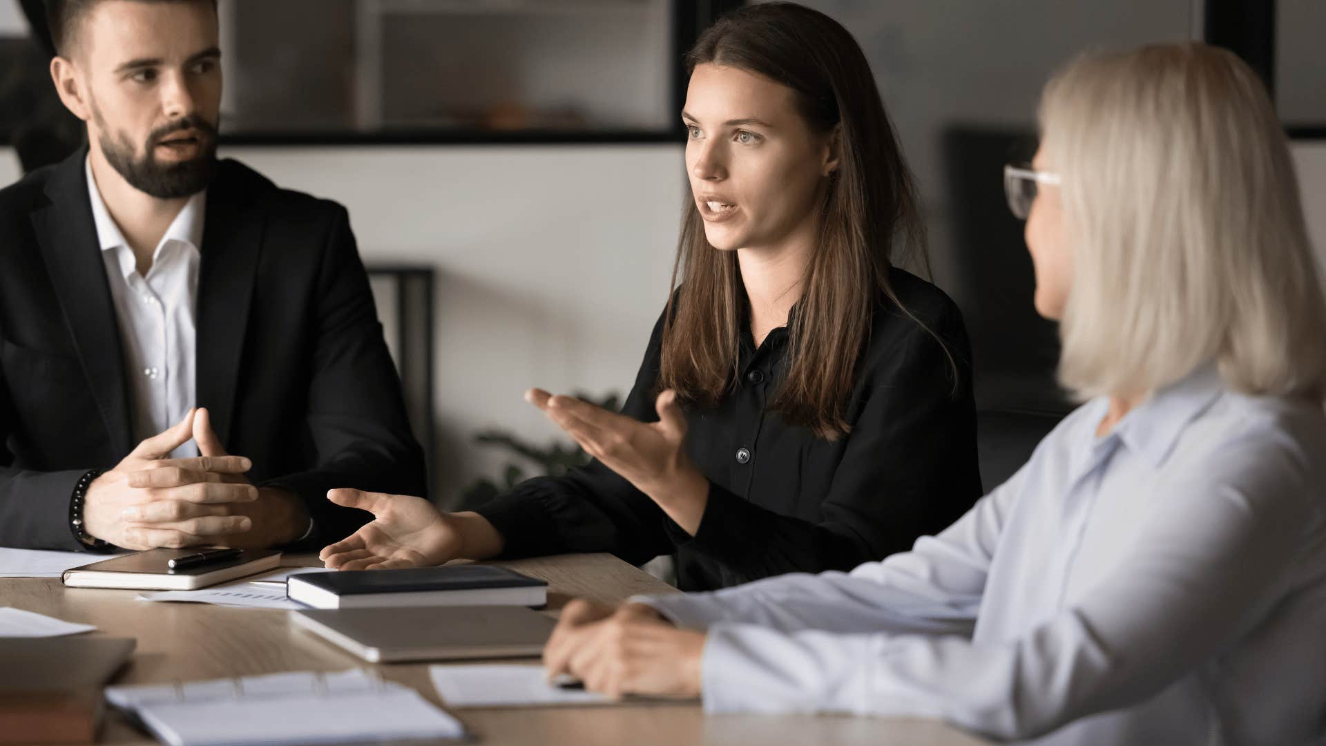 woman in black shirt in meeting talking as they noticed someone feels left out