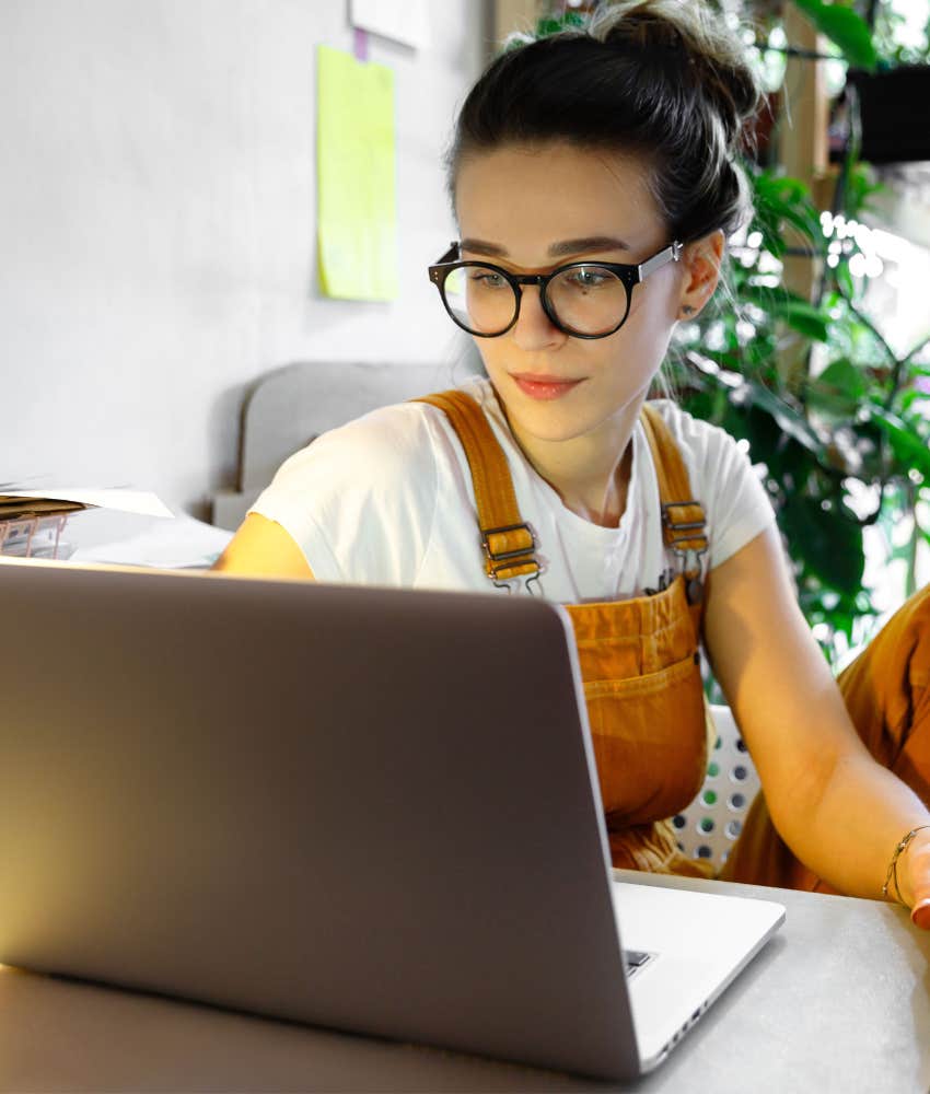woman in glasses working on a computer seems happy