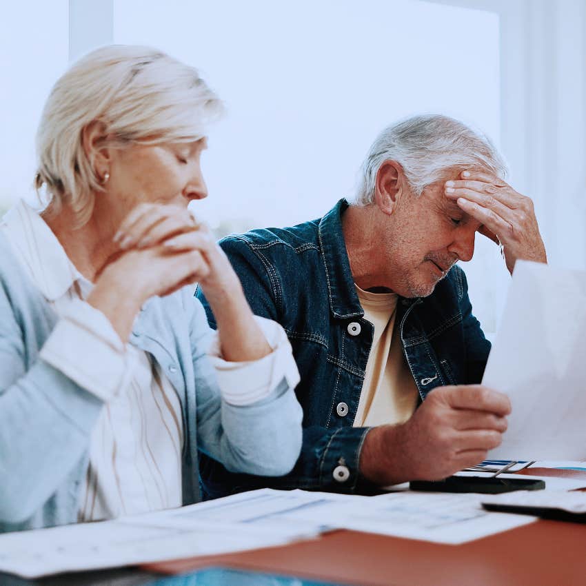 Tense man collapsing their posture at home doing bills.