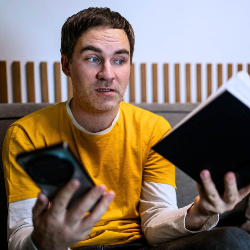 Man struggling to read physical media while scrolling on his phone.