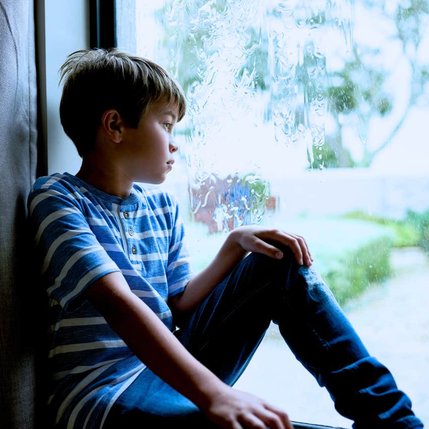 sad little boy looking out the window unable to trust his parents
