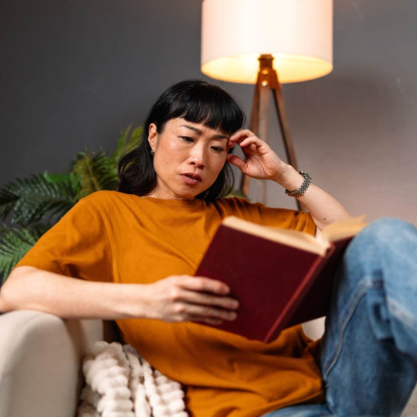 woman at home reading because her bigger paycheck has made her less extroverted