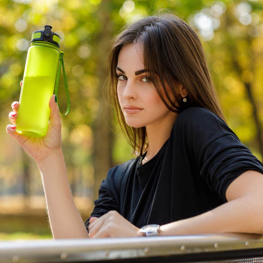 woman holding up a water bottle with disdain because she refuses to buy one