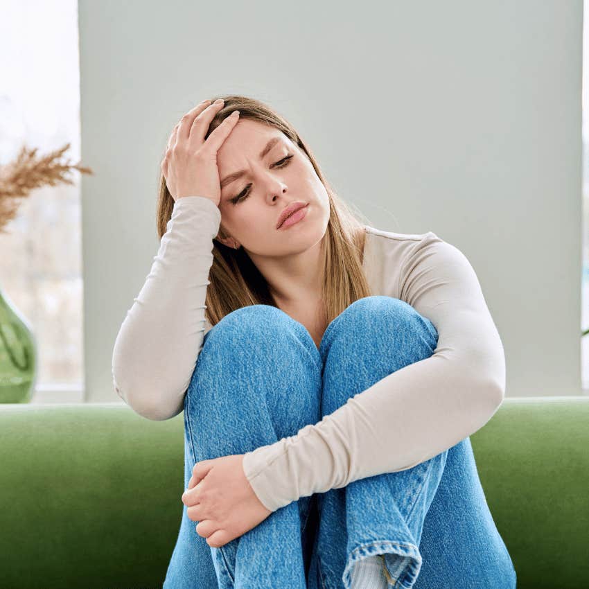 serious woman sitting on couch feeling alone