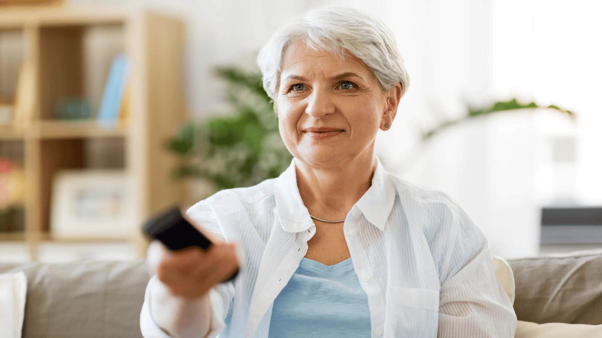 boomer woman flipping through channels watching tv
