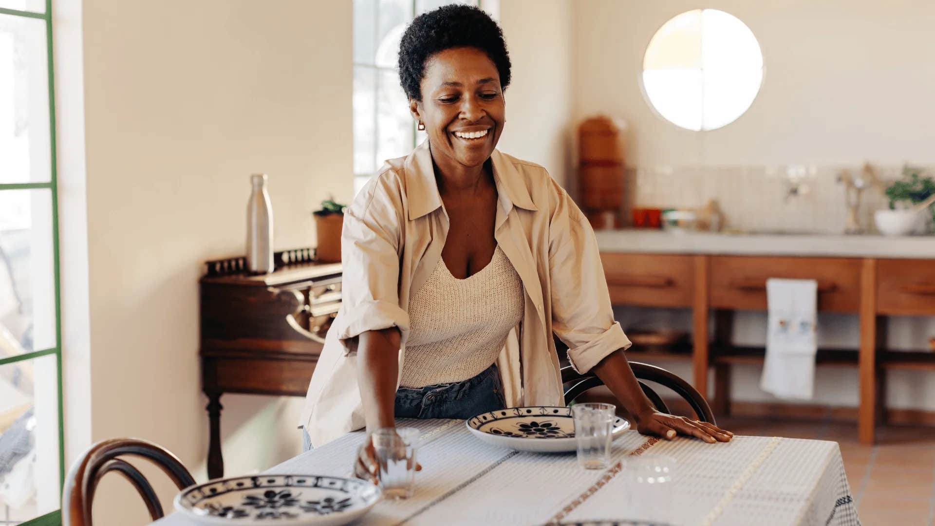 older woman setting out fine china for dinner