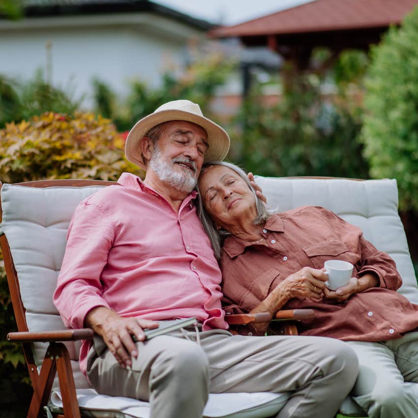 mature couple showing each other affection snuggling on lounge chair in backyard