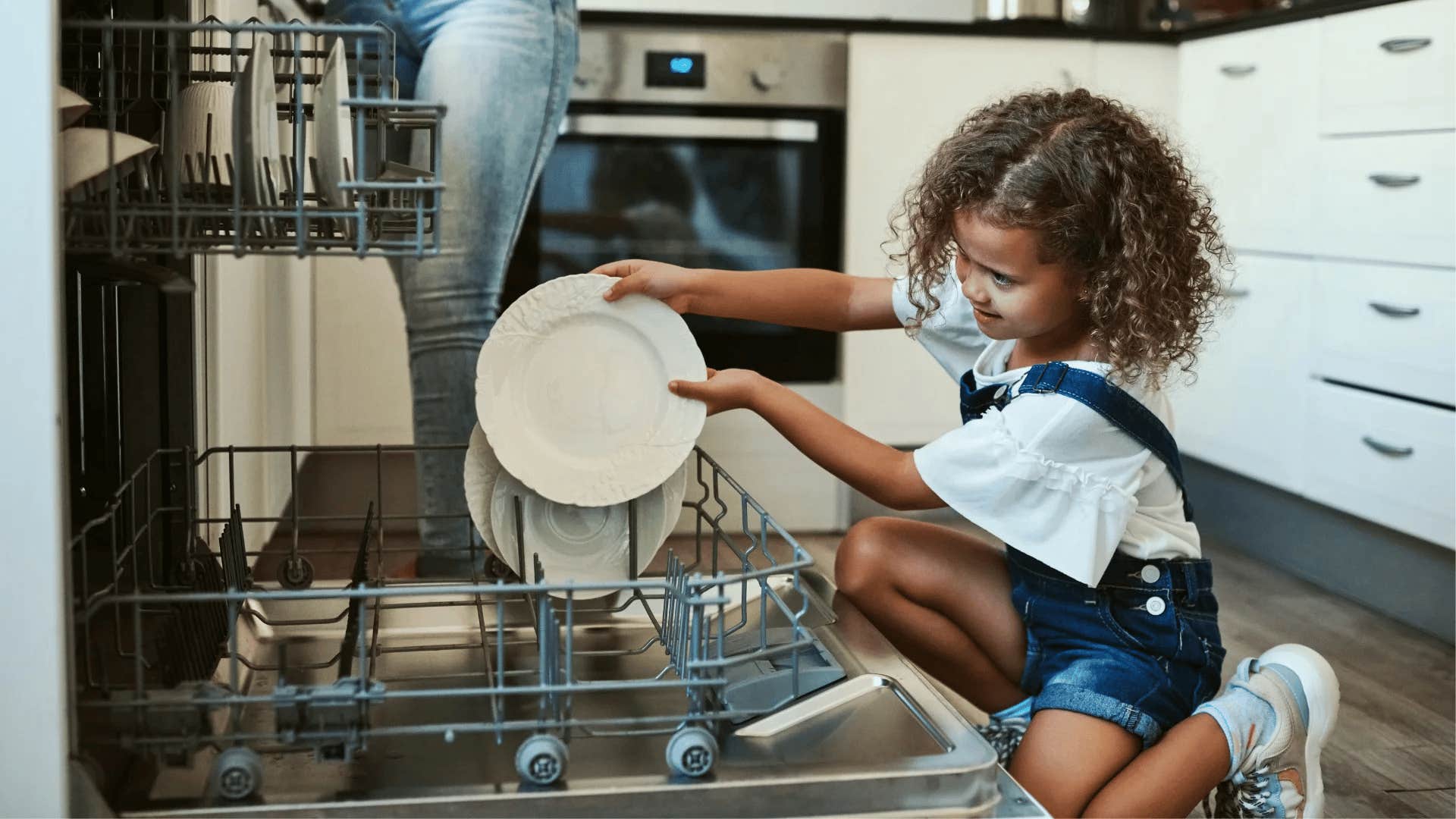 young girl loading the dishwasher as part of her chores