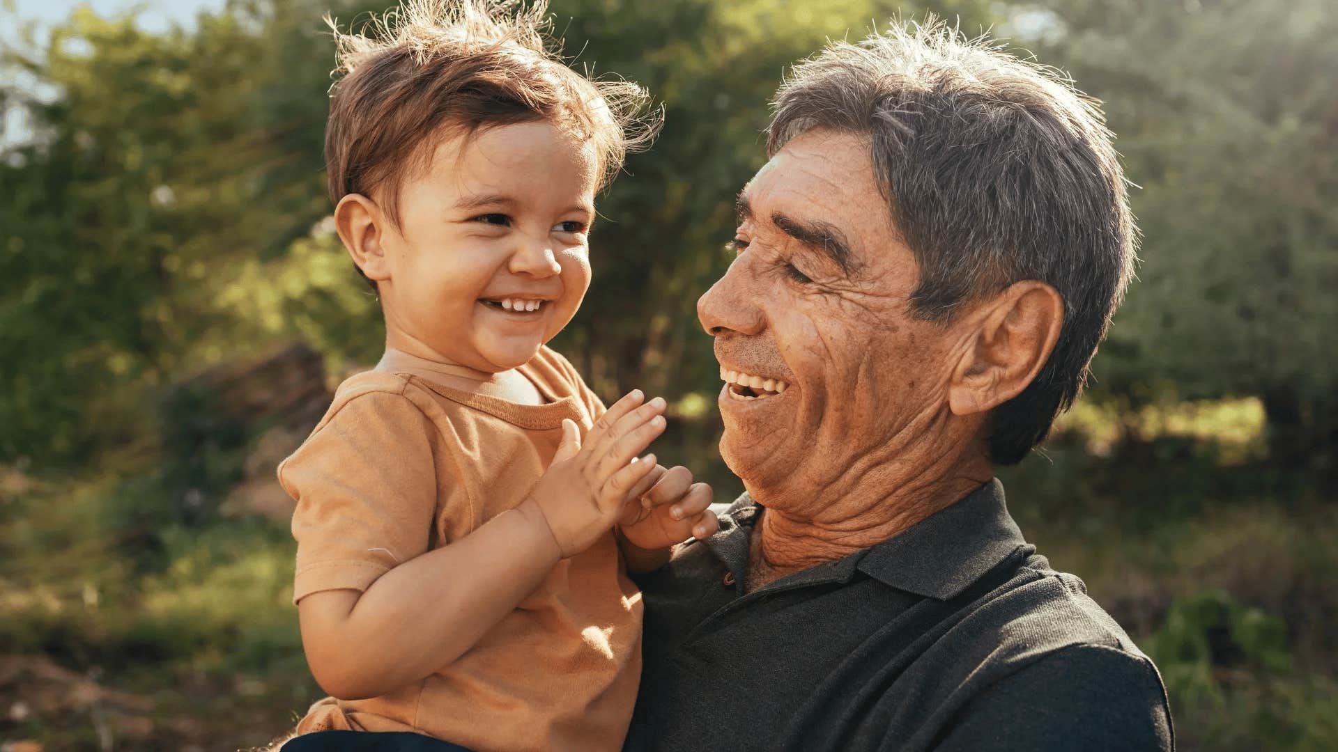 happy older man holding his smiling grandchild
