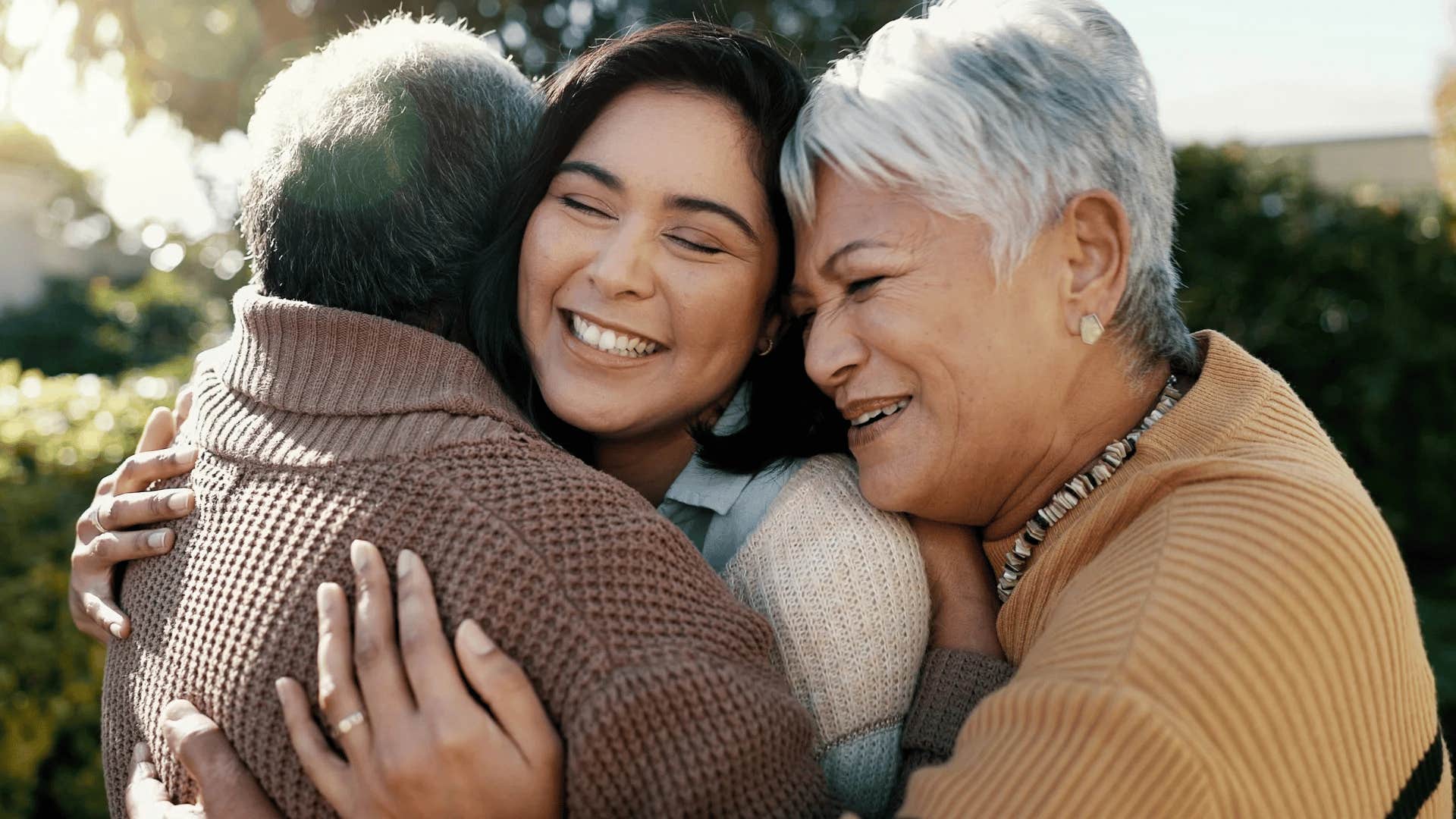 grandparents hugging their adult granddaughter making good memories together