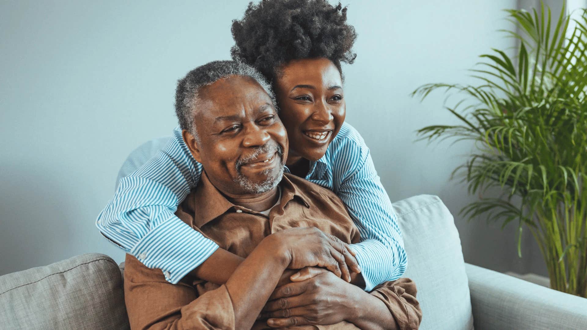 smiling woman hugging her grandfather from behind