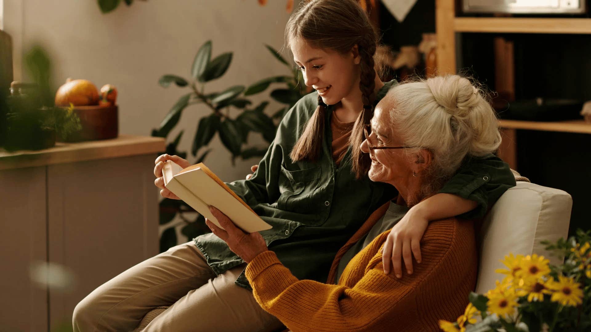 granddaughter sitting next to grandmother teaching her skills and reading to her