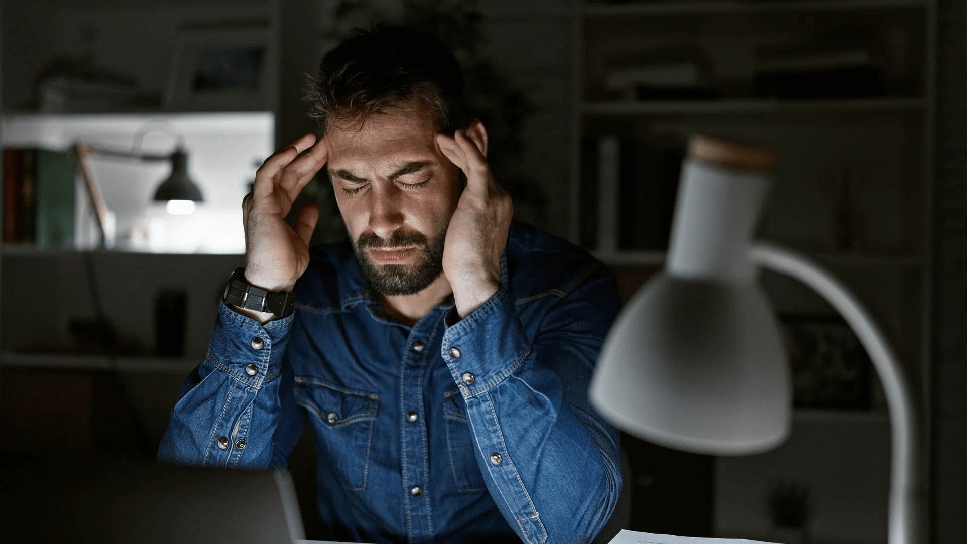 intelligent man struggling with the pressures to succeed sitting in the dark
