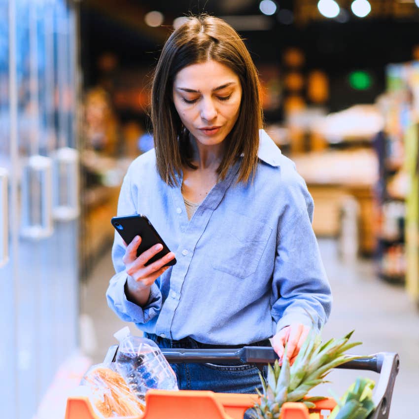 lonely woman reliant on her phone shopping at the grocery store