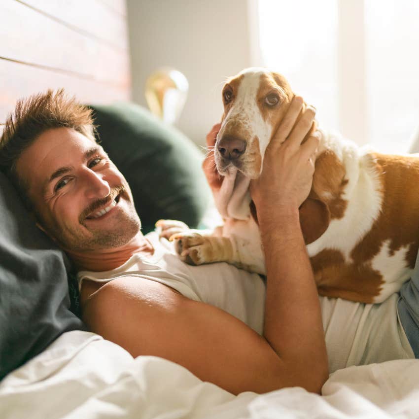 man snuggling with his dog in bed 