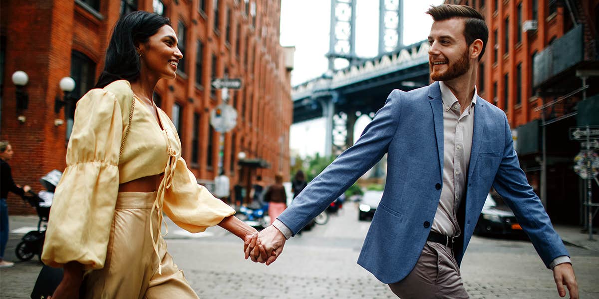 happy couple holding hands walking in city