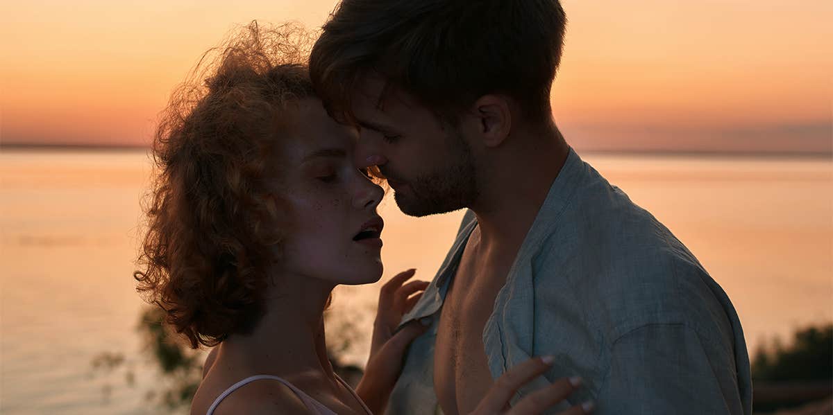 man and woman kissing by the sunset