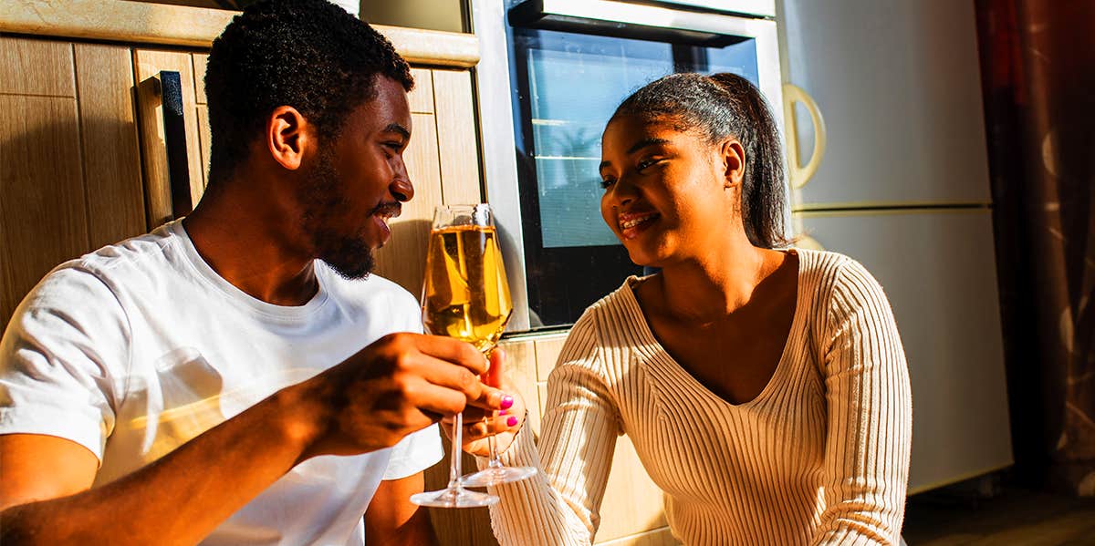 man and woman drinking wine in kitchen