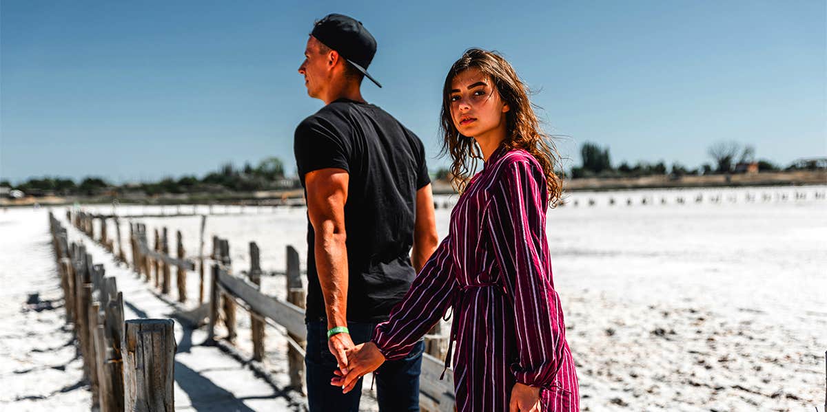 man and woman holding hands walking on beach 