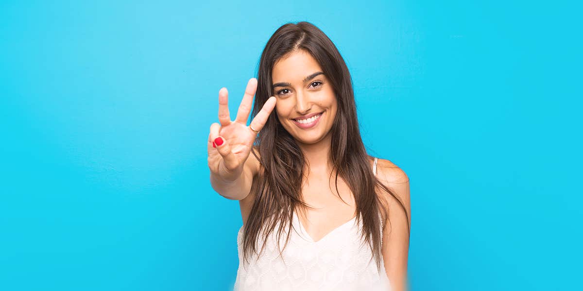 Why "3" Is The Magic Number In Relationships woman holding the three gesture