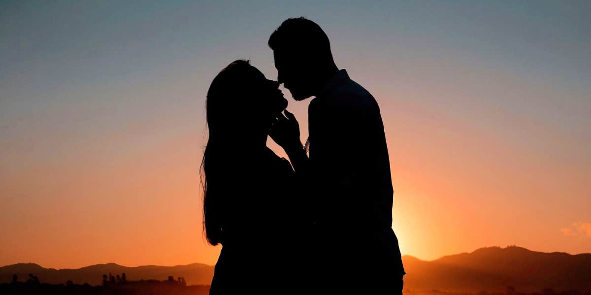 silhouette of man and woman kissing at sunset