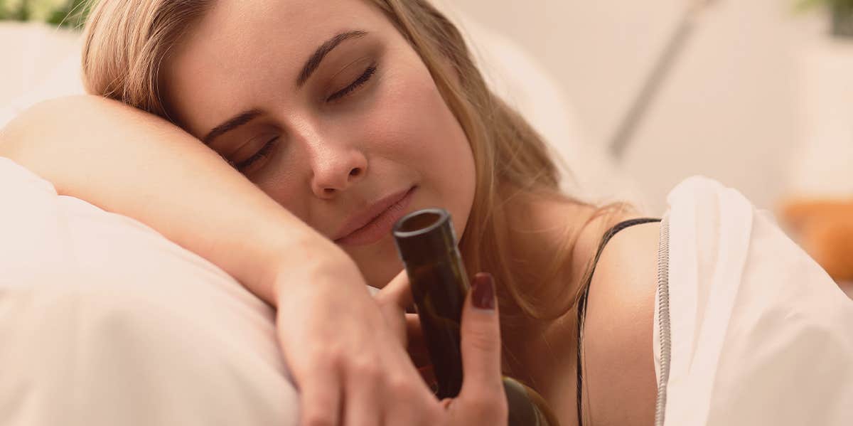 woman holding a bottle in bed