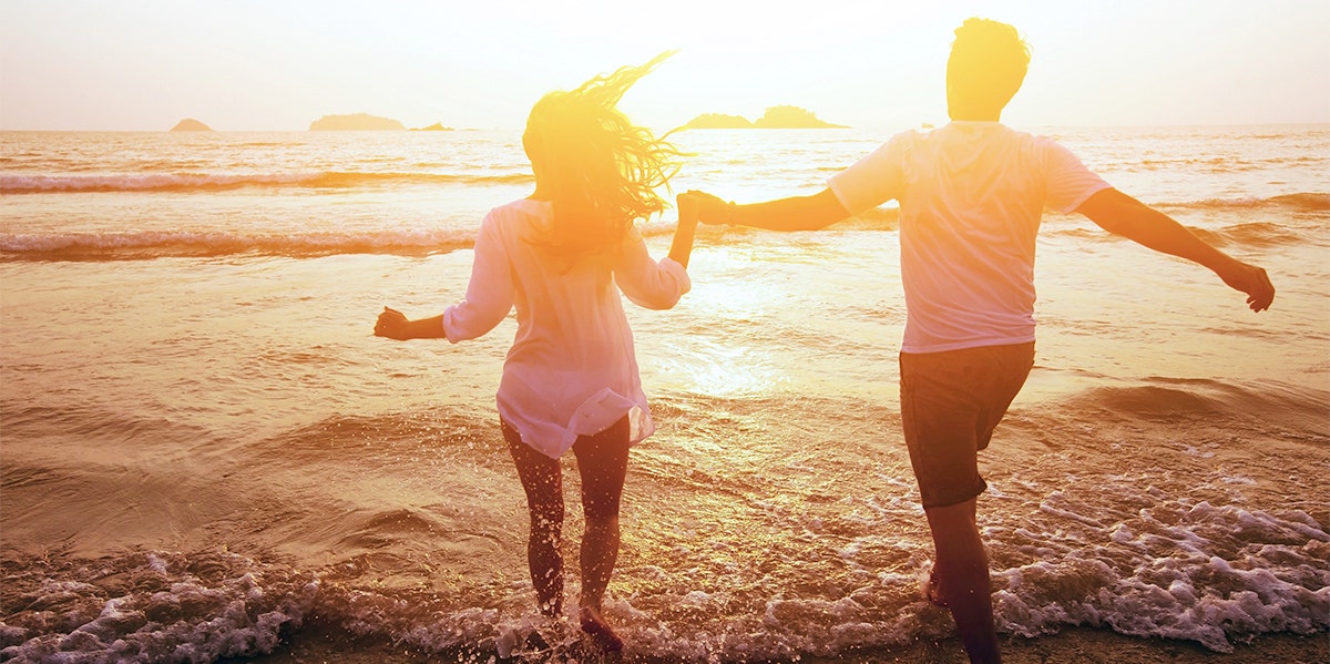 man and woman running into ocean